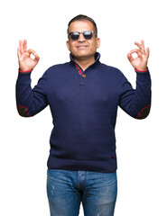 Naklejka premium Middle age arab man wearing sunglasses over isolated background relax and smiling with eyes closed doing meditation gesture with fingers. Yoga concept.