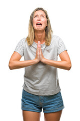 Fototapeta premium Young beautiful woman over isolated background begging and praying with hands together with hope expression on face very emotional and worried. Asking for forgiveness. Religion concept.
