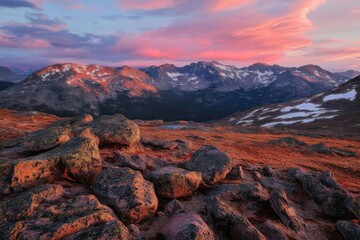 Colorful sunset over rocky mountains with vibrant clouds and rugged terrain.