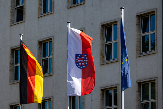 Vor dem Th&uuml;ringer Ministerium f&uuml;r Umwelt, Energie und Naturschutz in Erfurt wehen die Flaggen von Deutschland, Th&uuml;ringen und der EU, die die regionale und europ&auml;ische Zusammenarbeit symbolisieren.