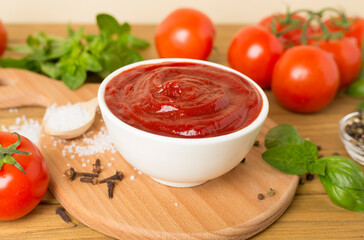 Delicious ketchup with spices and tomatoes on wooden table