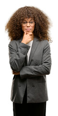 African american business woman wearing glasses looking confident at the camera with smile with crossed arms and hand raised on chin. Thinking positive.