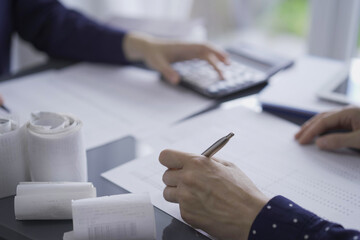 Two accountants or auditors reviewing financial data in office. Professionals analyzing paper reports and using calculators. Audit and taxes in business