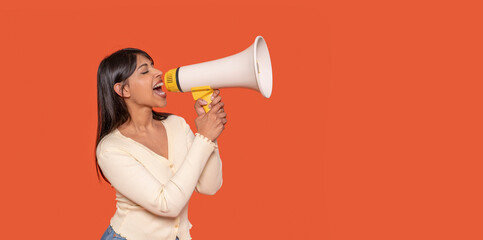 Woman Enthusiastically Using a Megaphone Against Vibrant Orange Background