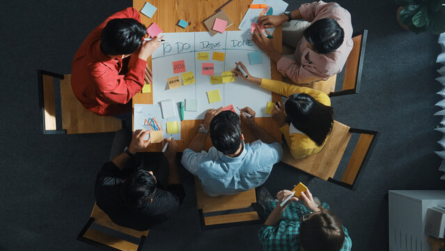 Top view of people writing and making scrum task board while writing marketing and planning strategy at colorful sticky notes. Smart team manage work performance by using kanaban board. Convocation.