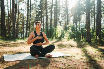 Young caucasian woman doing yoga stretching and meditating in forest


