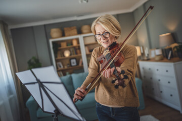 Mature senior caucasian woman learn to play violin practice at home © Miljan Živković