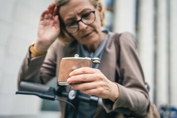 mature caucasian woman with flask alcohol abuse and alcoholism concept