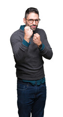 Fototapeta premium Young handsome man wearing glasses over isolated background Ready to fight with fist defense gesture, angry and upset face, afraid of problem