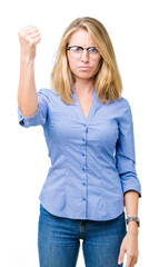 Beautiful young business woman over isolated background angry and mad raising fist frustrated and furious while shouting with anger. Rage and aggressive concept.