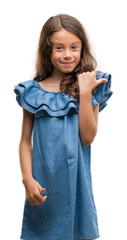 Fototapeta premium Brunette hispanic girl wearing denim dress pointing and showing with thumb up to the side with happy face smiling
