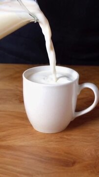 Leite sendo despejado em uma ch&aacute;vena de porcelana