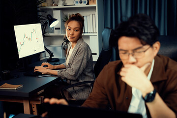 Businessman with stressful face working on laptop waiting email while coworker discussing together for consult at late night time at modern office, working on startup company project job. Infobahn.