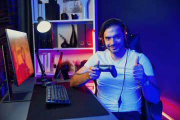 Smart gaming streamer with joystick player looking at camera, playing battle team shooting gun background at warship on pc screen at side view, wearing headset at digital neon light studio. Surmise.