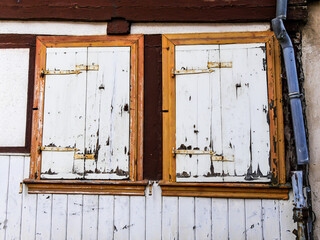 Zwei alte Fensterläden am Fachwerkhaus und ein kaputtes Fallrohr