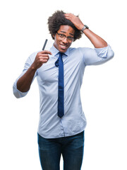 Fototapeta premium Afro american man holding credit card over isolated background stressed with hand on head, shocked with shame and surprise face, angry and frustrated. Fear and upset for mistake.