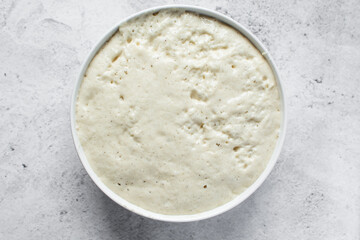Overhead view of nigerian puff-puff dough that has proofed, puff-puff dough in a white mixing bowl, process of making puff-puff or bofrot