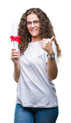 Young brunette girl holding degree and wearing glasses over isolated background happy with big smile doing ok sign, thumb up with fingers, excellent sign