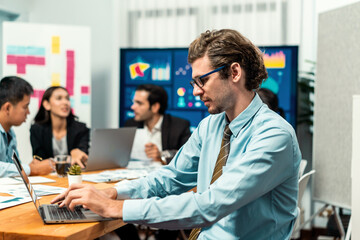 Portrait of businessman or analyst looking at camera with his colleague analyzing data analysis in dynamic business strategy investment planning meeting. Meticulous