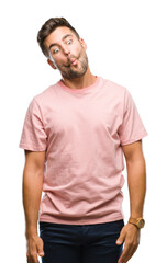 Young handsome man over isolated background making fish face with lips, crazy and comical gesture. Funny expression.