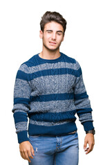 Young handsome man over isolated background winking looking at the camera with sexy expression,...