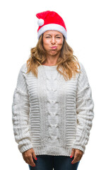 Middle age senior hispanic woman wearing christmas hat over isolated background puffing cheeks with funny face. Mouth inflated with air, crazy expression.