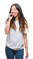 Fototapeta premium Young asian woman eating pink macaron sweet over isolated background with a confident expression on smart face thinking serious