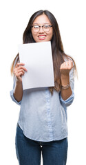 Young asian woman holding blank paper over isolated background screaming proud and celebrating victory and success very excited, cheering emotion