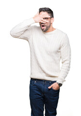 Fototapeta premium Young handsome man wearing glasses over isolated background peeking in shock covering face and eyes with hand, looking through fingers with embarrassed expression.