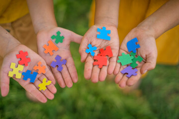 Multicolor paper puzzles in the hands of children. The symbol of development, education, represents the sign of autism