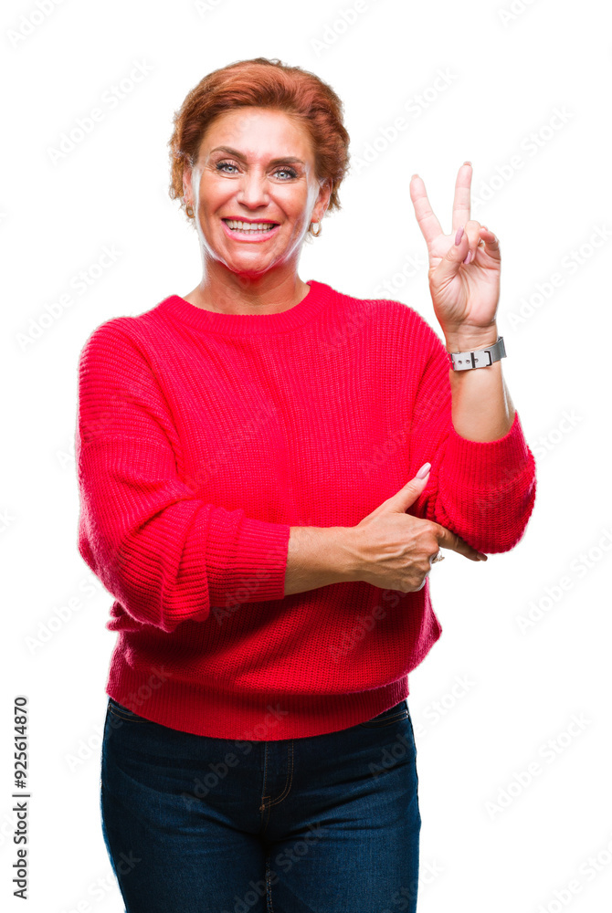 Wall mural Atrractive senior caucasian redhead woman wearing winter sweater over isolated background smiling with happy face winking at the camera doing victory sign. Number two.