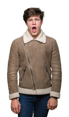 Young handsome man wearing winter coat over isolated background In shock face, looking skeptical and sarcastic, surprised with open mouth