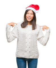 Young asian woman wearing christmas hat over isolated background looking confident with smile on face, pointing oneself with fingers proud and happy.