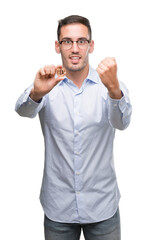 Fototapeta premium Handsome young man holding bitcoin screaming proud and celebrating victory and success very excited, cheering emotion