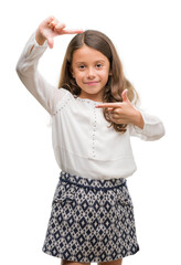 Brunette hispanic girl smiling making frame with hands and fingers with happy face. Creativity and photography concept.