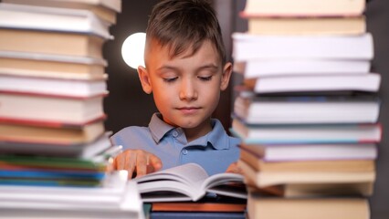 Young boy reading book surrounded by stacks of books