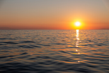 Fototapeta premium The gorgeous golden sun descends towards the horizon, casting a warm and mesmerizing glow over the tranquil waves of the ocean, creating a breathtaking and serene scene.