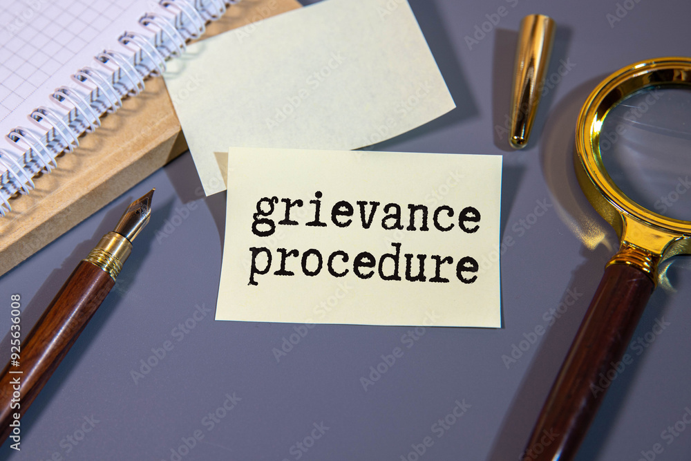 Poster text grievance procedure on notepad with office tools, pen on financial report .