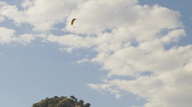 Several paragliders soar high in the sky under the bright sun, capturing a thrilling and adventurous moment against a clear blue backdrop.