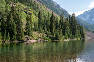 Maroon Bells reflected in Maroon Lake on sunny summer afternoon under dramatic summer cloudscape.