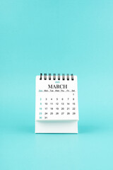 March 2025 white desk calendar on blue background.