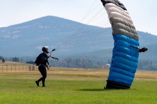 Woman skydive lands parachute in an open field in Montana