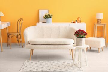 Obraz premium Interior of stylish living room with white sofa and chrysanthemum flowers on coffee table