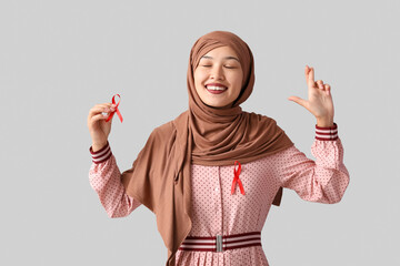 Beautiful Muslim woman with red ribbons on grey background. AID awareness concept