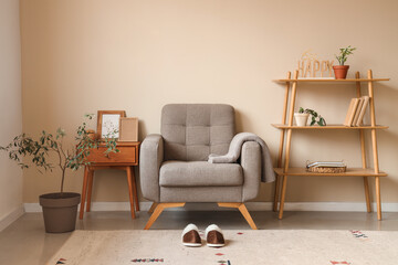 Pair of soft slippers on carpet near armchair in modern living room