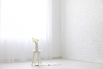 Coffee table with flowers and light curtains in white room