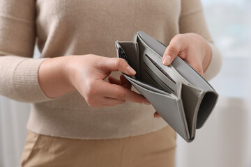 Woman with empty wallet indoors, closeup view