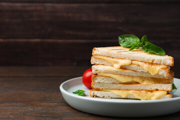 Pieces of toasted bread with melted cheese and basil on wooden table, space for text