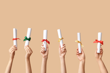 Female hands with diplomas on beige background