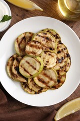 Tasty grilled courgette slices served on wooden table, flat lay